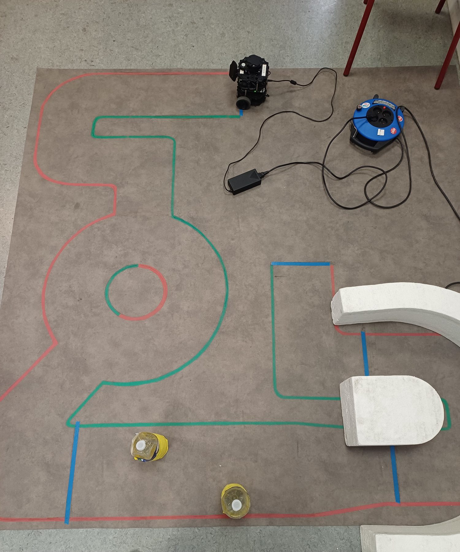 The physical course seen from above: red, green and blue tape, a roundabout and a corridor